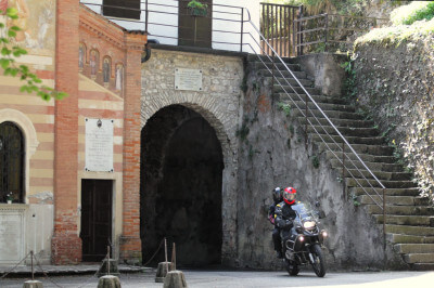 Motorradfahrer mit Sozia fährt durch Tunnel unter der Kirche Madonna di Rio Secco