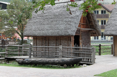 Mit Stroh gedeckte neu aufgebaute Pfahlhütten am Ledrosee