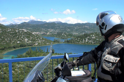 Motorradfahrer blickt über blaue Seen und BergeKroatien