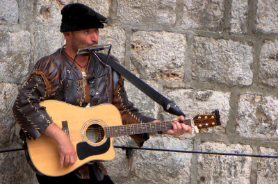 Straßenmusikant spielt Munharmonika und dazu Gitarre in der Altstadt von Dubrovnik