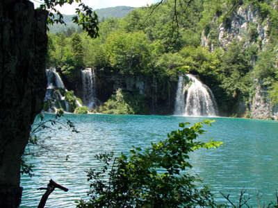 Blick über einen der Plitvicer-Seen im Hintergrund mit Wasserfall