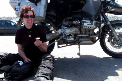 Frau sitzt im Schatten eines Motorrades und probiert marokkanische Wurst