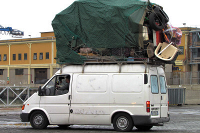 Schwer beladener Ford-Transit-Transporter mit Dachlast mit Stühlen, Tischen usw.