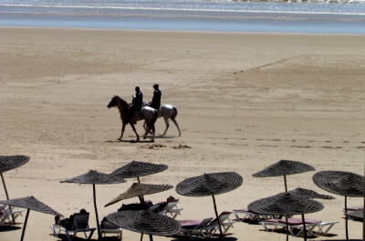 Zwei Polizisten reiten auf ihren Pferden am Strand von Essaouira entlang
