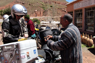 Motorradfahrer und Händler stehen vor einem Souvenirladen und verhandeln über Preis