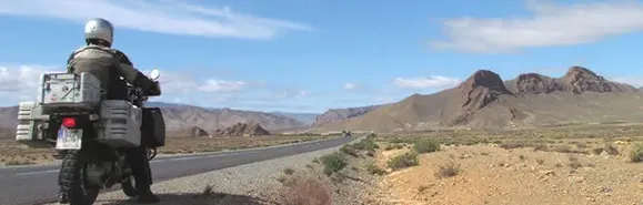Hoher Atlas voraus Motorrad steht am Seitenstreifen und am Horizont ist der Hoher Atlas zu sehen