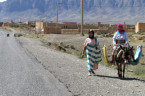Frauen laufen mit Esel am rechten Fahrbahnrand im Hohen Atlas