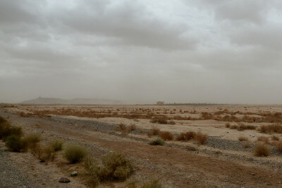 Straße durch wüstenartige Landschaft mit Sandverwehungen