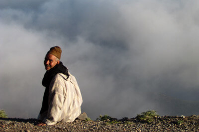 Berber sitzt vor Abgrund und schaut rückwärts am Tizi-n-Test