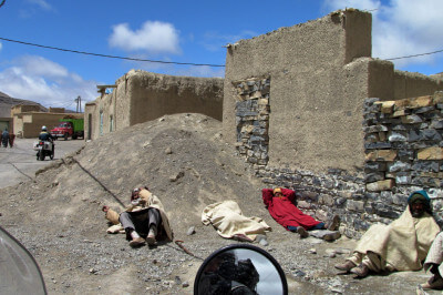 In Djellabas gekleidete Berber liegen vor ihren Häusern und machen Pause