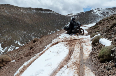 Motorrad kehrt um auf einer schneebedeckten offroad Piste in den Bergen