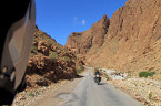 Hinterher fahrender Motorradfahrer auf Straße zwischen hohen Felsen in der Todra-Schlucht