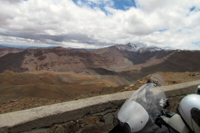 Panoramablick mit Motorrad vor Steinmauer auf der Passhöhe des Tizi-n-Tirherhouzine