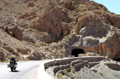 Tunnel der Legionäre Motorrad mit Fahrer und Sozia fährt in felsiger Landschaft auf denTunnel der Legionäre zu