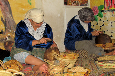Frauen produzieren sitzend diverse Arganprodukte in buntem Laden