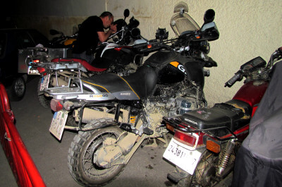 Etliche Motorräder und Roller stehen nachts auf einem bewachten Parkplatz in Fes