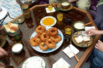 Reich gedeckter Frühstückstisch aus Glas mit Teigkringel im Riad