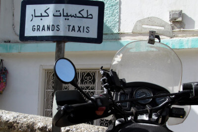 Motorrad parkt vor Schild Grands Taxis