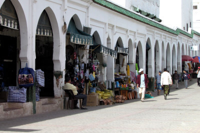 Blick entlang einer mit Rundbögen verzierten Einkaufsstraße mit kleinen Läden