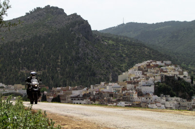 Straße mit Motorrad oberhalb von Moulay Idris in bergiger bewachsener Landschaft