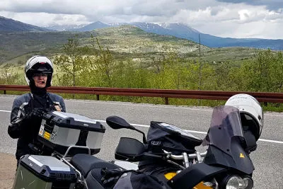 Nicht mehr weit bis zur Bucht von Kotor. Wir riechen das Wasser schon. Oder ist es der Regen? Motorradfahrerin steht bei Pause hinter dem Motorrad am Straßenrand