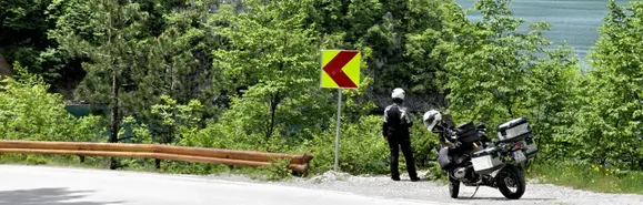 Piva-Stausee - eines der Highlights des ersten Tages in Montenegro. Motorrad steht auf Parkbucht und Motorradfahrerin blickt auf den Piva-Stausee