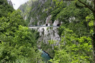 Die Uferstraße an der Piva pendelt schwungvoll durch freien Fels, um dann dutzendmal in Naturtunnels zu verschwinden. Blick auf die Brücke der Straße mit Tunnel um den Pivastausee