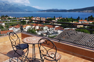 Dachterrasse mit zwei Stühlen und einem Tisch und Blick über die Hausdächer von Kotor auf die Bucht