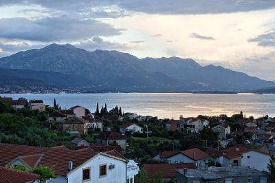 Blick über Häuser hinweg auf Berge mit Meer an der äußeren Boka Kotorska