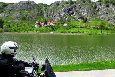 Motorradfahrer steht an einem See kur