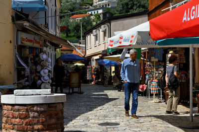 Mann läuft durch Ladengasse in Stari Bar. Vorne ein kleiner Backsteinbrunnen