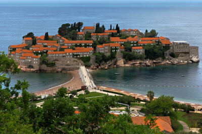Kleine, der Küste vorgelagerte Insel komplett bebaut mit der Hotelanlage Sveti Stefan mit roten Dächern