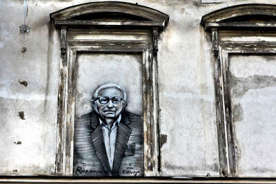 Aufgemaltes Portrait einer Person in einem gemauerten Fensterrahmen an einer Häuserfront in Breslau