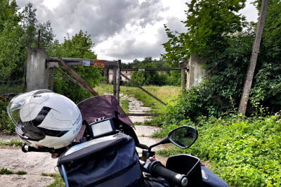 Motorrad mit Helm am Lenker steht vor dem verschlossenen Eingangstor von Schloss Schlobitten