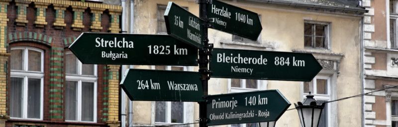 Hinweisschilder auf Entfernungen zu einzelnen Städten vor Haus in Polen