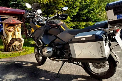 Motorrad parkt bei einem Rastplatz vor einer Holzschnitzerei
