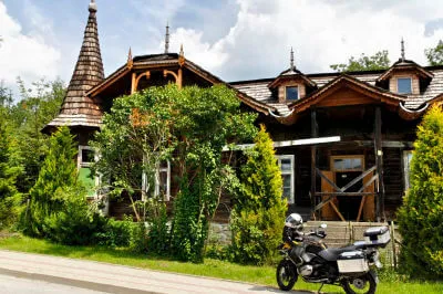 Motorrad steht vor Haus im typischen Baustil aus Holz mit kleinem Türmchen der Waldkarpaten