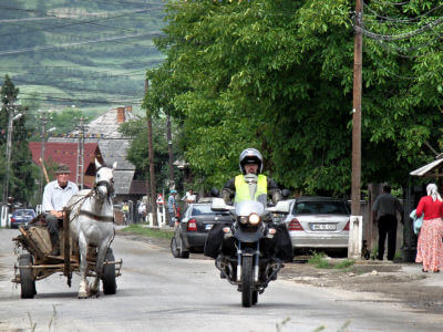 Motorrad überholt Pferdefuhrwerk in einem Dorf im Iza-Tal