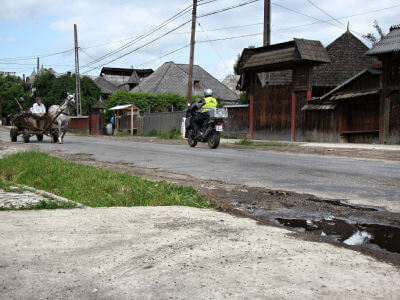 Pferdefuhrwerk im Gegenverkehr zum Motorrad in einem Dorf in der Maramures