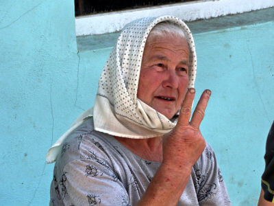 Marktfrau zeigt zwei Finger in die Höhe im Markt in Vișeu de Sus