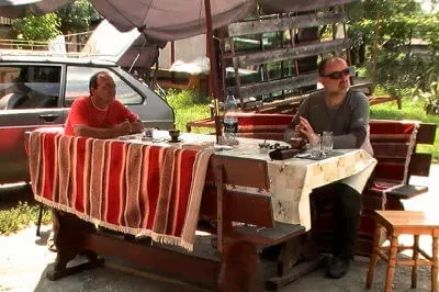 Gastfreundschaft: wir werden mit Getränken versorgt, während wir auf den Abschlepper warten. Zwei Männer sitzen an Gartentisch und warten auf den Abschlepper