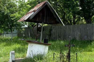 Ein Hausbrunnen an der Straße in Oltenien. Überdachter runder Hausbrunnen steht auf einer Wiese
