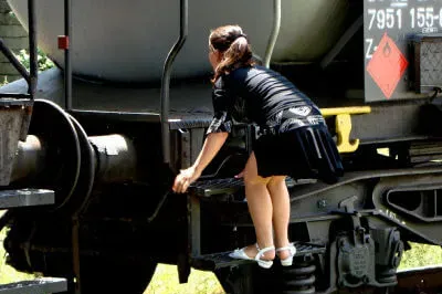 Wenn der Bahnübergang nicht frei ist, wählt man andere Wege ... Mädchen klettert über Wagon von Eisenbahn