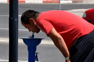 Straßenszene in Târgu Jiu Mann trinkt Wasser aus einem Brunnen an der Straße