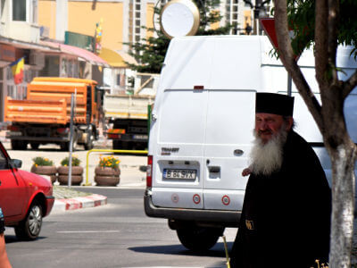 Ein Geistlicher möchte hinter einem Lieferwagen die Straße in Târgu Jiu überqueren