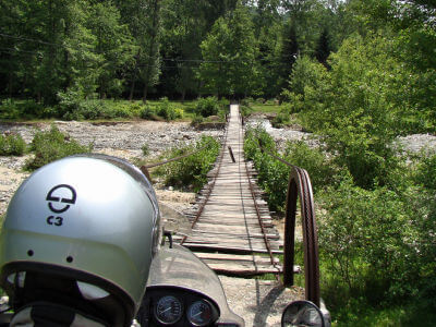 Motorradfahrer steht vor für den Verkehr gesperrten Holzbrücke