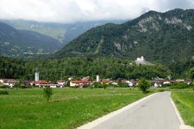 Kirche Sveti Anton und das dazugehörige Beinhaus. Man erreicht es von Kobarid aus in einer halbstündigen Wanderung - oder mit dem Motorrad etwas schneller. Kirche Sevti Anton auf kleinem Berg. Im Hintergrund mehr Berge und Dorfansicht von Kobarid.
