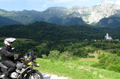 Motorradfahrer vor Bergkette mit Dorf im Hintergrund