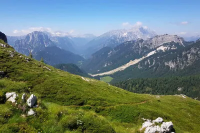 Hier oben herrscht bei herrlichstem Sonnenschein eine Temperatur von 18 Grad - das ist eine klasse Alternative, um den Temperaturen da unten im Tal zu entfliehen. Und die Sonnenauf- und -untergänge, von denen träumt jeder Romantiker. Talblick über grüne Wiese auf die slowenische Alpen von der Mangartstraße aus