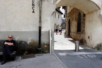Auf einer Bank vor dem Stadttor. Der Stadtkern ist so gut wie autofrei. Nur Anwohner haben eine Fernbedienung, um die Poller zu versenken. Altes Stadttor von Skofja Loka